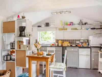 a kitchen with white cabinets and a wooden table at The Shepherd's Hut in Aberdyfi