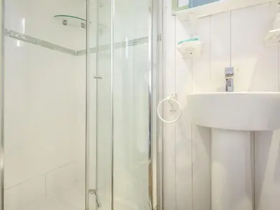 a white bathroom with a shower and a sink at The Shepherd's Hut in Aberdyfi