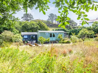 a green house in the middle of a field at The Shepherd's Hut in Aberdyfi