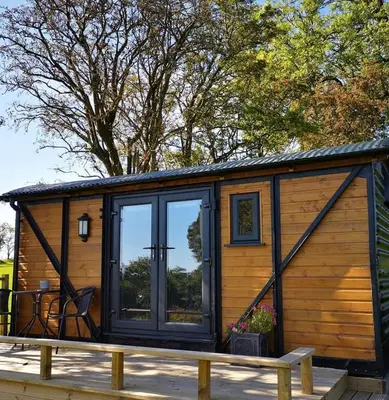 a tiny house with a large window on a deck at pen-rhos luxury glamping 