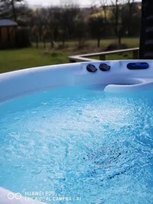 a bath tub filled with blue water with two black glasses at pen-rhos luxury glamping 