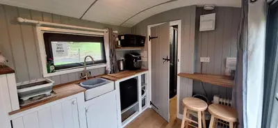 a kitchen with white cabinets and a sink and a window at pen-rhos luxury glamping 