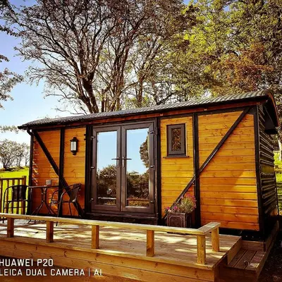 a wooden cabin with a large window on a deck at pen-rhos luxury glamping 