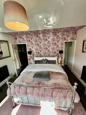 a bedroom with a large bed with pink wallpaper at Gamelin in Llangollen