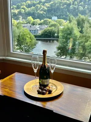 a bottle of champagne and two glasses on a table with a window at Gamelin in Llangollen