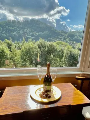a bottle of wine and two glasses on a table with a window at Gamelin in Llangollen