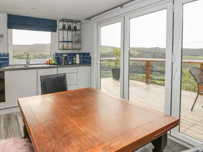 a kitchen with a wooden table and a balcony at Haka Lodge in Aberystwyth