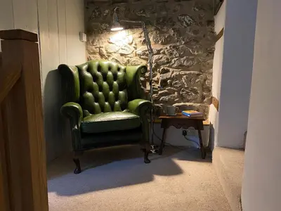 a green chair in a room with a table at Peniarth Ganol in Tywyn