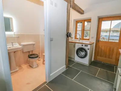 a bathroom with a washing machine and a washer and dryer at Peniarth Ganol in Tywyn