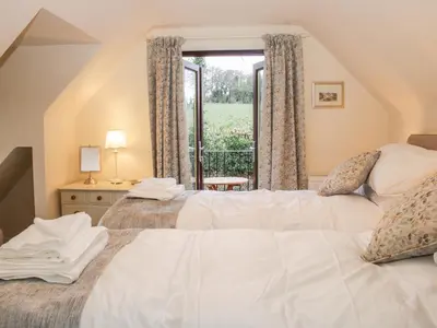 two beds in a room with a window at Oakland Cottage in Craven Arms