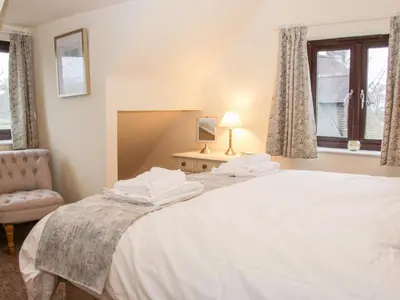 a bedroom with a bed and a chair and a window at Oakland Cottage in Craven Arms