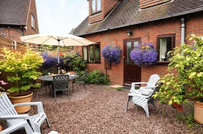 a patio with a table and chairs and an umbrella at Oakland Cottage in Craven Arms