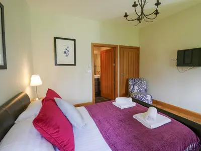 a bedroom with a large bed with a purple blanket at Yr Hen Beudy in Aberystwyth