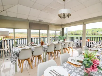 a dining room with tables and chairs and windows at Llety Ceiro in Bow Street