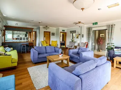 a living room with blue couches and a table at Llety Ceiro in Bow Street