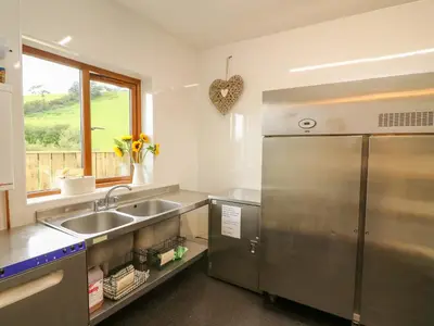 a kitchen with a stainless steel refrigerator and a sink at Llety Ceiro in Bow Street