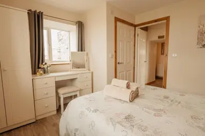 a bedroom with a bed and a desk and a window at Bennar Isa Cottages Dyffryn Ardudwy in Barmouth