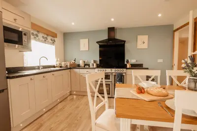 a kitchen with a table and a stove top oven at Bennar Isa Cottages Dyffryn Ardudwy in Barmouth
