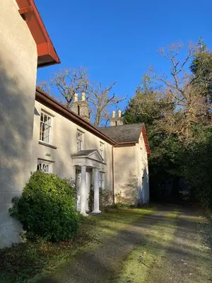 an old white house with a driveway in front of it at Plas Dolau Country Estate in Aberystwyth