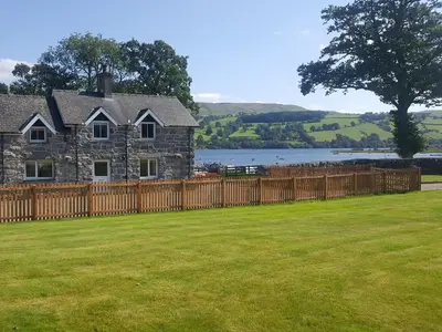 a house with a wooden fence in front of a yard at Bwthyn Glanllyn in Llanuwchllyn