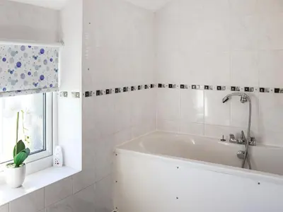 a white bathroom with a tub and a window at Bwthyn Glanllyn in Llanuwchllyn