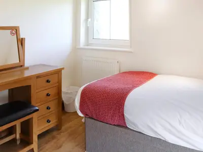 a bedroom with a bed and a dresser and a mirror at Bwthyn Glanllyn in Llanuwchllyn