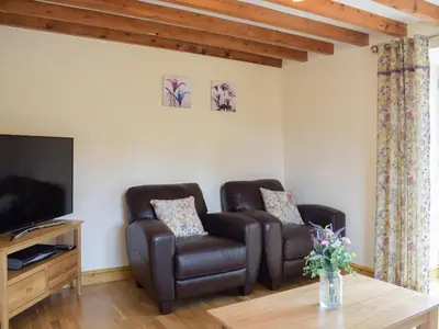 a living room with two chairs and a television at Bwthyn Glanllyn in Llanuwchllyn