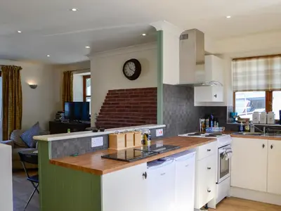 a kitchen with white cabinets and a clock on the wall at Ty Cregyn - Uk11957 in New Quay