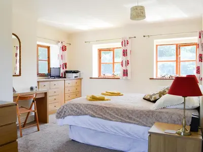 a bedroom with a bed with a desk and a kitchen at Ty Cregyn - Uk11957 in New Quay