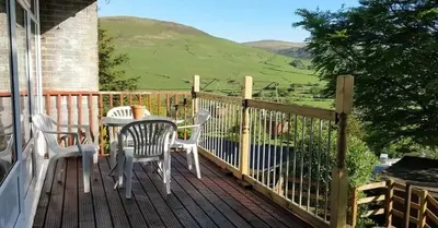 a wooden deck with a table and chairs on a house at Springside Chalet20 in Tywyn