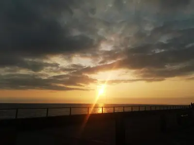 a sunset over a pier with the sun shining at Springside Chalet20 in Tywyn