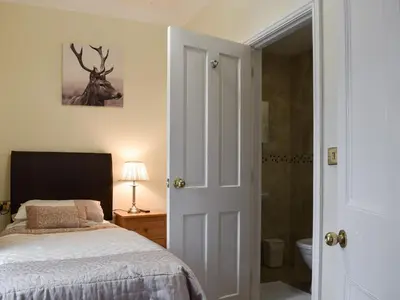 a bedroom with a bed and a bathroom with a deer picture at Maesbangor Farmhouse in Capel Bangor