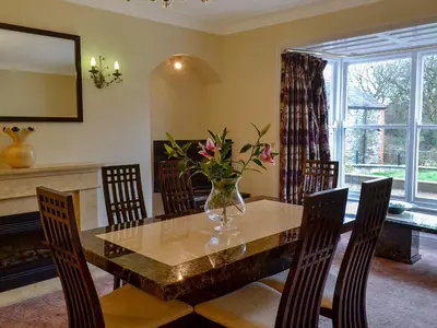a dining room with a table with a vase of flowers on it at Maesbangor Farmhouse in Capel Bangor