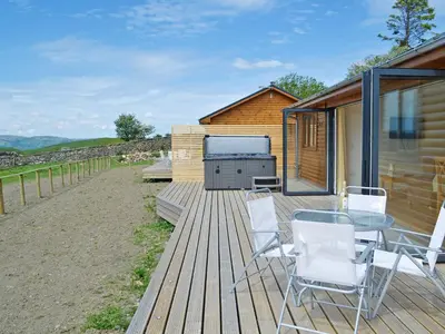 a deck with a table and chairs and a barbecue at Sweet Meadow Lodge in Llandrindod Wells