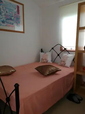 a bedroom with a bed with pink sheets and pillows at Chalet Kiss of the Sea in Aberystwyth