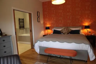 a bedroom with a bed and a red wall at Cwmbach Lodge luxury B&B in Glasbury
