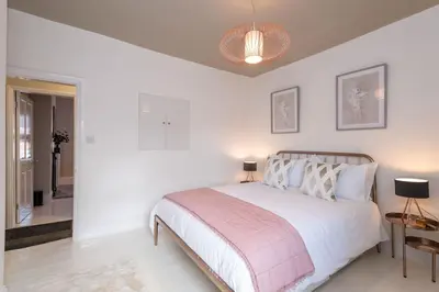 a white bedroom with a bed with a pink blanket at Cherry Orchard in Shrewsbury