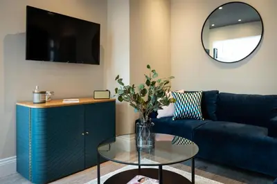 a living room with a blue couch and a glass table at Cherry Orchard in Shrewsbury