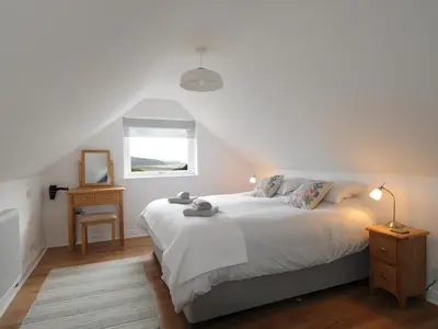 a bedroom with a white bed and a window at Bryn Derw in Barmouth