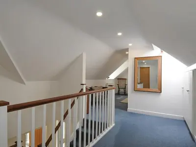 a hallway with a staircase with a mirror on the wall at Bryn Derw in Barmouth
