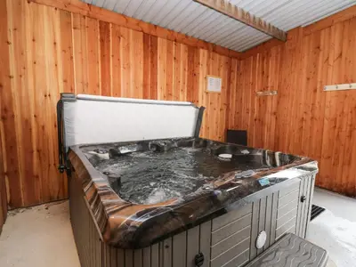a hot tub in a room with wooden walls at Y Felin - Celyn in Borth