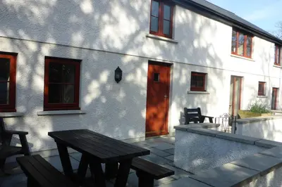a patio with a wooden table and a building at Kestrel Farmhouse in Llandovery