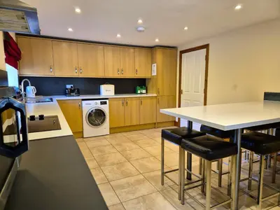 a kitchen with wooden cabinets and a table with stools at Kestrel Farmhouse in Llandovery