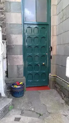a green door with a bowl of flowers in front of a door at Ground Floor Barmouth Centre Apartment With Garden in Barmouth