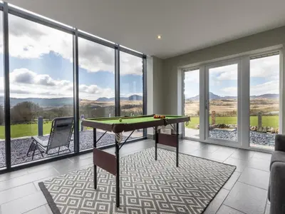 a living room with a pool table and glass windows at Cartref in Trawsfynydd