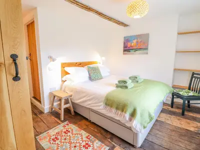 a bedroom with a bed with a green blanket on it at Cefn Nannau in Corwen