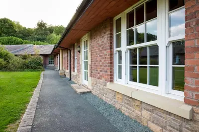 a brick building with white windows and a sidewalk at Netley Hall in Shrewsbury