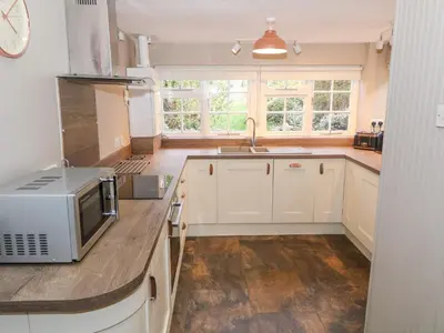 a kitchen with white cabinets and a microwave on a counter at Fro Awel in Dolgellau