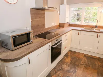 a kitchen with white cabinets and a microwave on a counter at Fro Awel in Dolgellau
