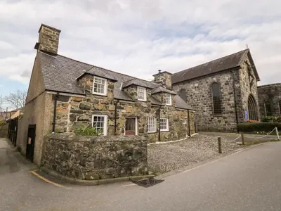 an old stone building with a stone wall in front of it at Fro Awel in Dolgellau